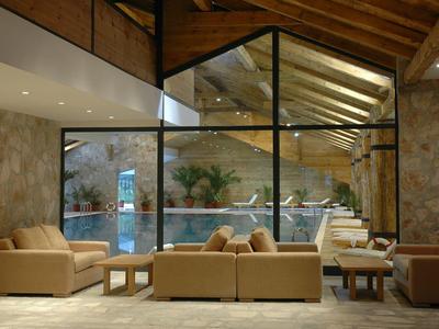 Gezellige lounge met leren banken en glasramen met uitzicht op een buitenzwembad.