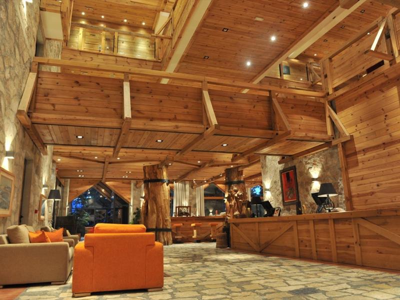 Interieur van een hotellobby met houten plafond en zitgedeeltes met oranje banken.