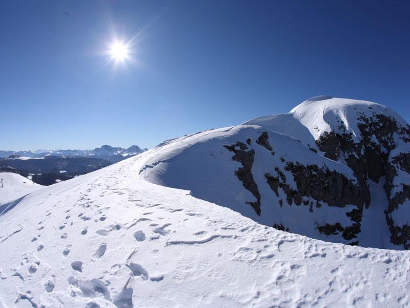 Zonnige dag op een met sneeuw bedekte berg met een heldere blauwe lucht en bergtoppen op de achtergrond.