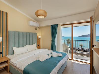 Camera d'hotel moderna con letto matrimoniale, balcone e vista mare.