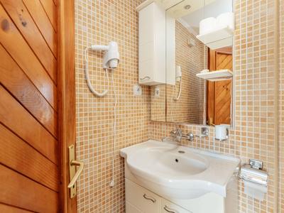 Luftaufnahme einer Küstenstadt mit roten Dächern, blauem Meer und einer kleinen Hafenanlage.