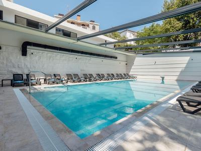 Piscina esterna moderna con lettini e pergolato in un'area dell'hotel.