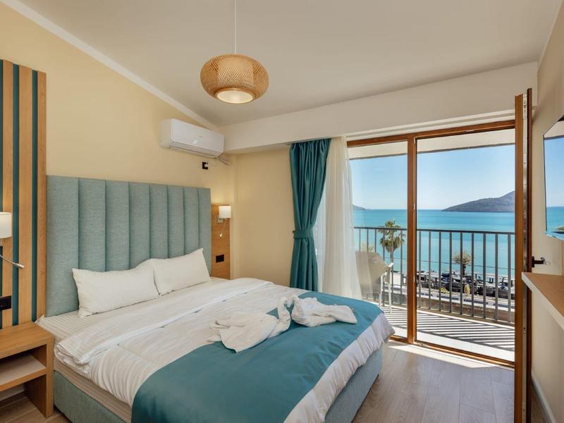 Modernes Schlafzimmer mit großem Bett, türkisfarbenem Kopfteil, Balkon und Meerblick.