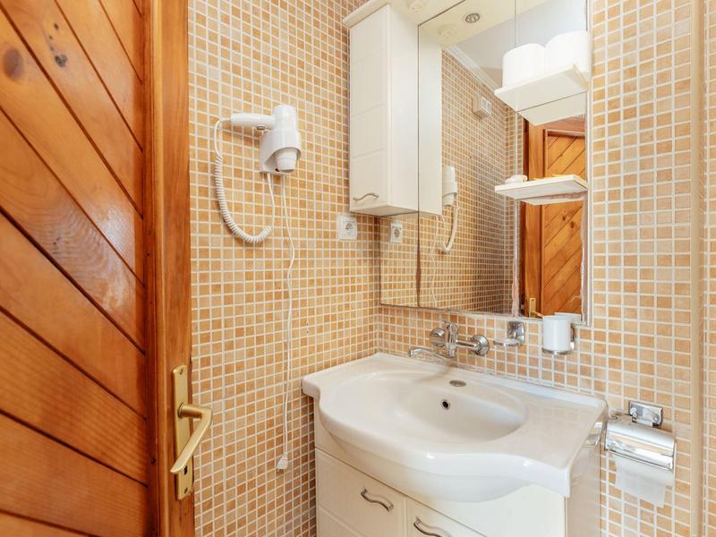 Luftaufnahme einer Küstenstadt mit roten Dächern, blauem Meer und einer kleinen Hafenanlage.