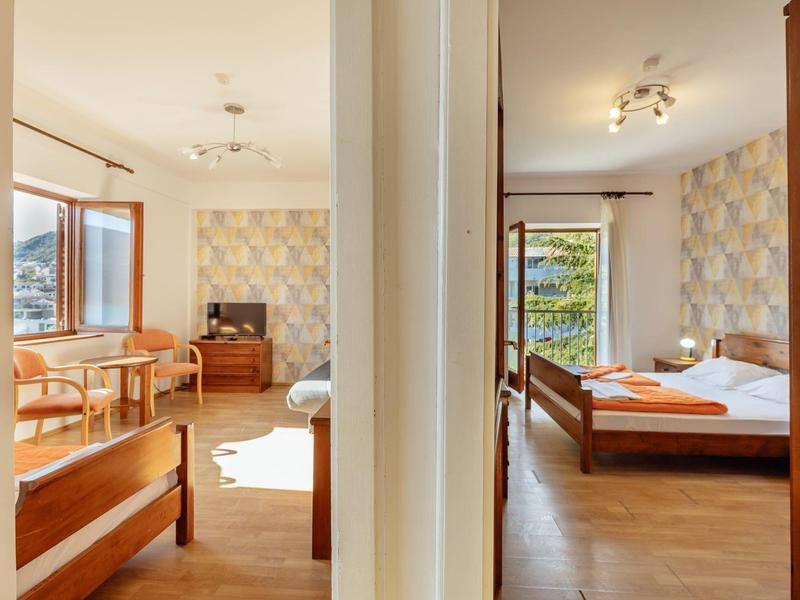 Zwei helle Schlafzimmer mit Holzbett, Teppich, Fenster und Naturblick, getrennt durch Wand.