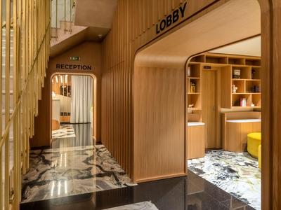 Moderner Hotel-Empfangsbereich mit Holzpanelen und Marmorboden.