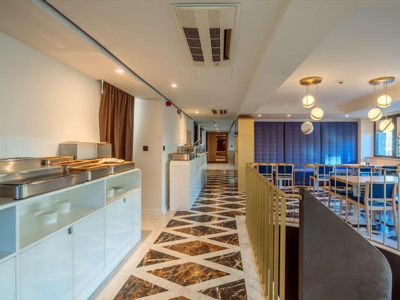 Moderner Restaurantflur mit weißer Seitenwand, gemustertem Boden und blauen Vorhängen.