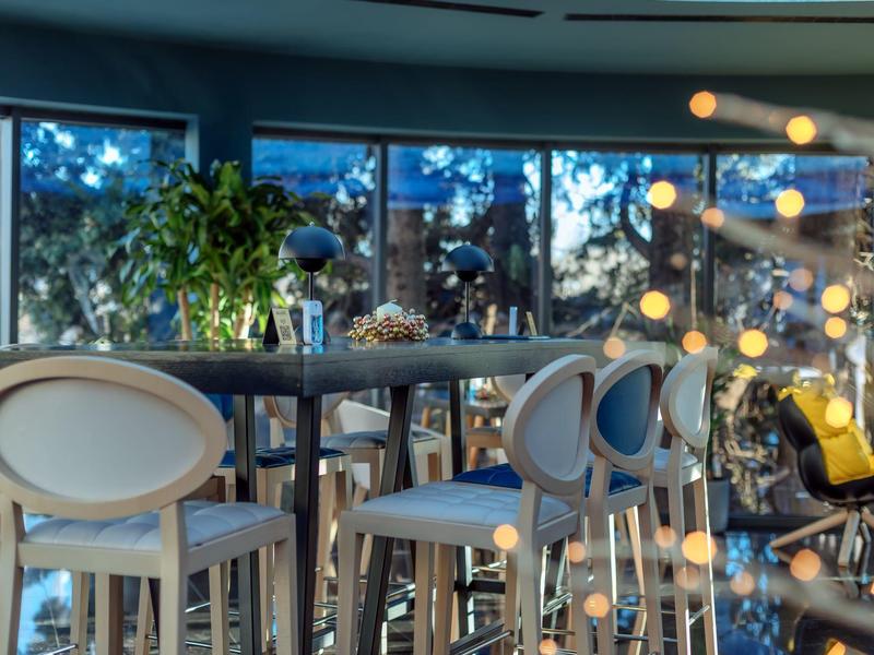 Modernes Esszimmer mit hellen Stühlen, großem Fenster und gemütlicher Beleuchtung mit Lichterkette.