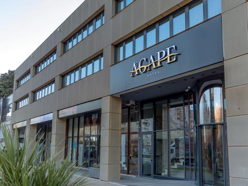 Modernes Bürogebäude mit Glasfront und dem Schriftzug "AGAPE" über dem Eingang.