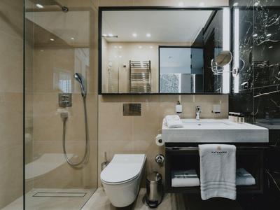 Modernes Badezimmer mit Duschkabine, weißer Toilette, Waschbecken und großem Spiegel.