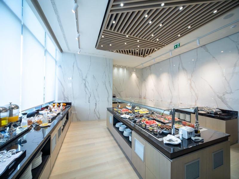Moderner Frühstücksraum mit Buffet, verschiedenen Speisen, Getränken und hellem, elegantem Interieur.