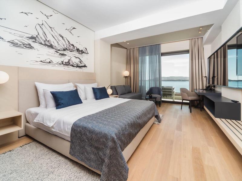 Modernes Hotelzimmer mit großem Bett, Holzfußboden, Sitzbereich und Panoramafenster.