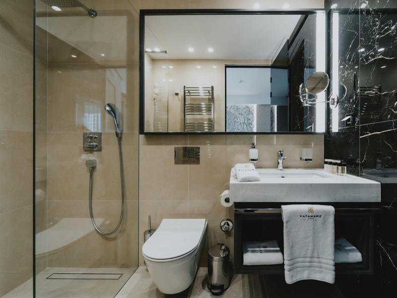 Modernes Badezimmer mit Duschkabine, weißer Toilette, Waschbecken und großem Spiegel.