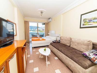 Gemütliches Wohnzimmer mit braunem Sofa, kleinem weißen Tisch und Flachbildfernseher an der Wand.