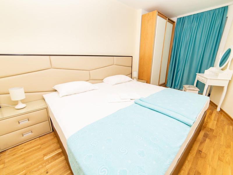 Helles Schlafzimmer mit Doppelbett, hellblauem Bettzeug, Nachttischlampen und kleinem Schminktisch.