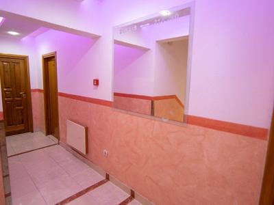 Corridor with pink-lit ceiling and wooden door frames in a hotel.