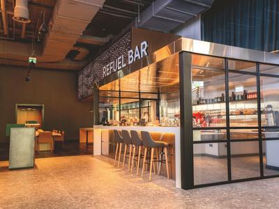 Moderne Hotelbar mit hohen Stühlen, Glaswänden und stilvoller Einrichtung.