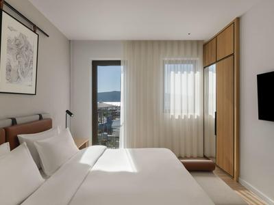 Moderner Hotelbarbereich mit runden orangen Barhockern und indirekter Beleuchtung.