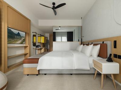 Modern eingerichtetes Hotelzimmer mit Doppelbett, hellem Holz und Deckenventilator.