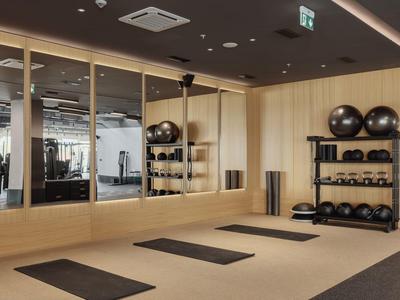 Moderne sportschool met matten en fitnessapparatuur in een lichte ruimte.