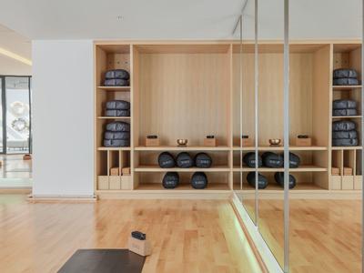 Moderne fitnessruimte met houten vloer en wandplanken voor gewichten in een lichte kamer.