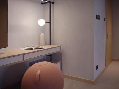 Moderner Hotel-Schreibtisch mit runder Hocker, Buch und runder Leuchte an der Wand.