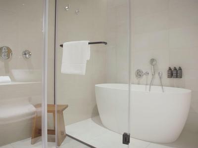 Moderner Badbereich mit freistehender Badewanne und Glasdusche in neutralen Tönen.