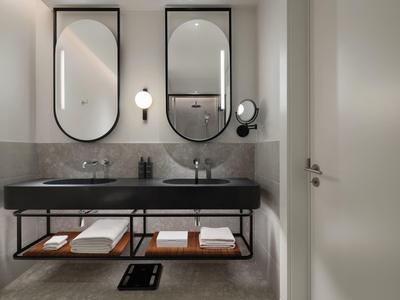 Modernes Badezimmer mit zwei Waschbecken, großen Spiegeln und Ablagefläche mit Handtüchern.