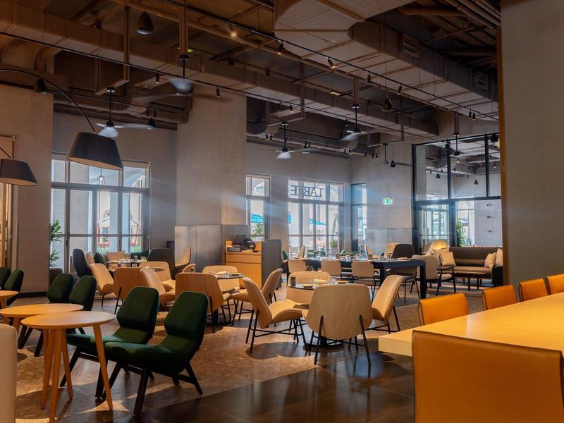 Moderner Speiseraum mit verschiedenen Stühlen und großen Fenstern in einem Hotel.