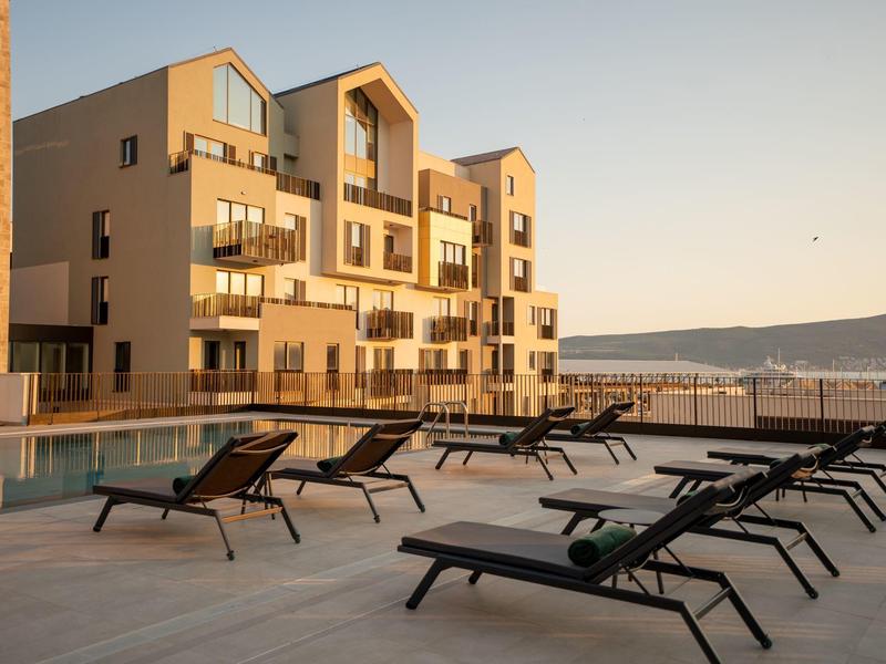 Moderne Hotelterrasse mit Liegestühlen und Blick auf das Meer bei Sonnenuntergang.