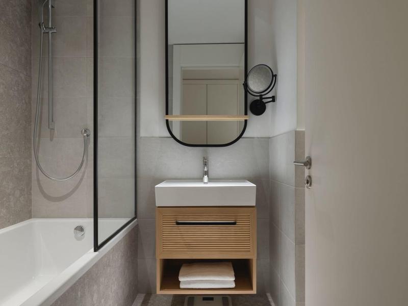 Kompaktes Badezimmer mit Badewanne, Glaswand und Spiegel über dem Waschbecken.