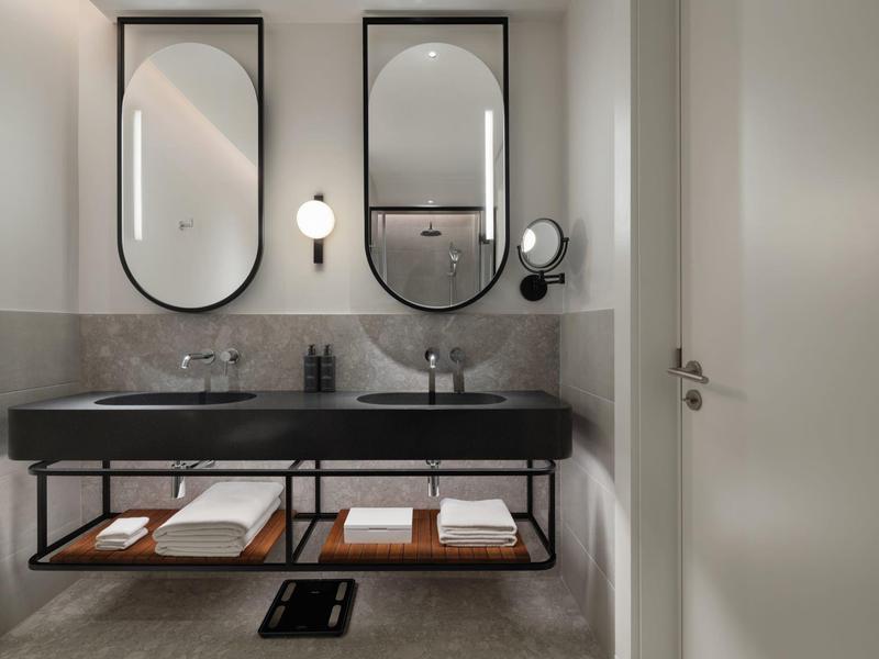 Modernes Badezimmer mit zwei Waschbecken, großen Spiegeln und Ablagefläche mit Handtüchern.