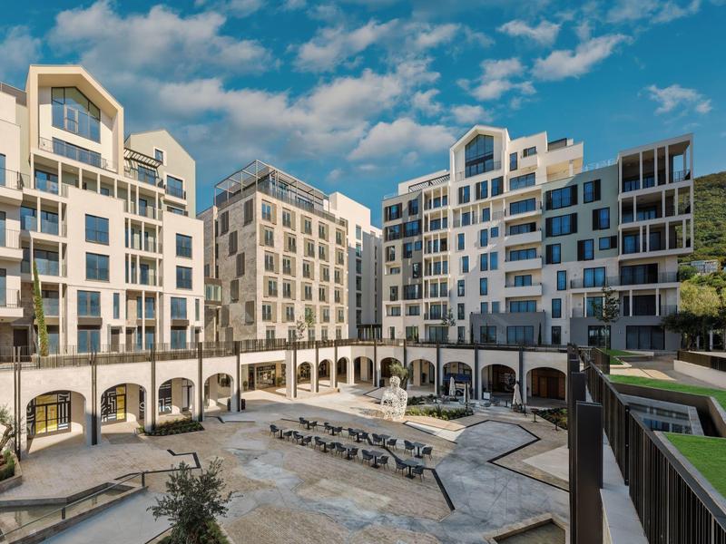 Moderner Hotelkomplex mit Terrasse und Liegestühlen unter blauem Himmel.