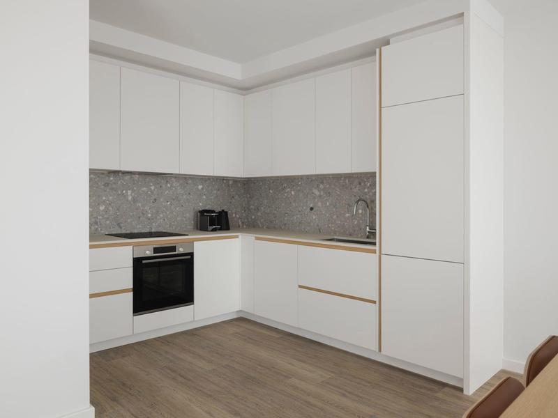 Moderne weiße Küche mit Holzarbeitsplatte, grauem Fliesenspiegel und Holzboden.