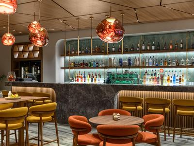 Bar d'hôtel conviviale avec chaises jaunes et orange et luminaires suspendus modernes.