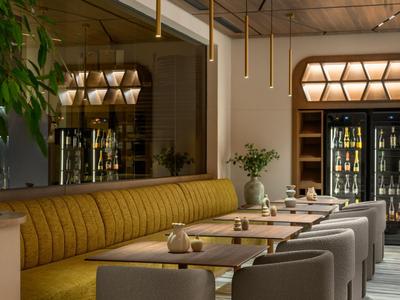 Restaurant moderne avec banquette jaune, chaises grises et suspensions décoratives.