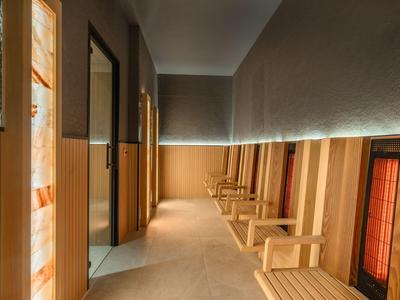 Couloir lumineux avec panneaux en bois et sièges, adapté aux hôtels ou espaces bien-être.