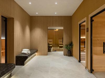 Espace bien-être spacieux d'hôtel avec saunas, boiseries et sièges confortables.