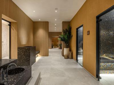 Couloir d'hôtel moderne avec murs chauds, sols en pierre et portes élégantes de salle de bain.