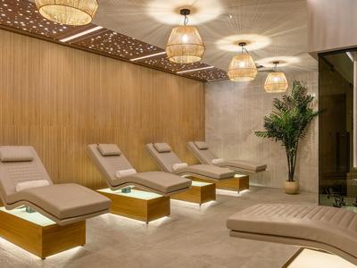 Espace détente confortable avec des chaises longues rembourrées, des accents en bois chaud et un éclairage doux.