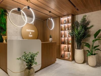 Réception de spa élégante avec comptoir minimaliste, plantes et design en bois chaleureux.