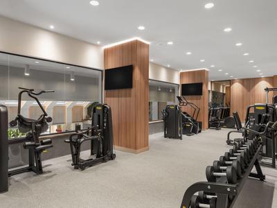 Salle de sport moderne avec haltères et machines de musculation dans un hôtel.