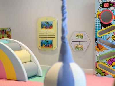 Espace de jeu pour enfants coloré avec un toboggan incurvé et des éléments muraux décoratifs.