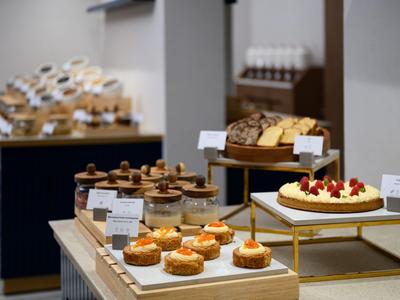 Différents desserts comme des gâteaux et tartes sur des présentoirs en bois et or dans un buffet élégant.