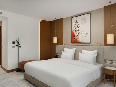 Modernes Hotelzimmer mit großem Bett, Holzpaneelen und minimalistischer Dekoration.