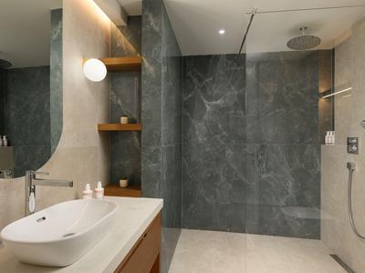 Modernes Badezimmer mit Waschtisch, ovalem Spiegel und begehbarer Dusche mit Regenduschkopf.