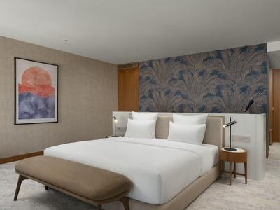 Modernes Hotelzimmer mit großem Bett, gepolstertem Kopfteil und dekorativer Wandgestaltung.