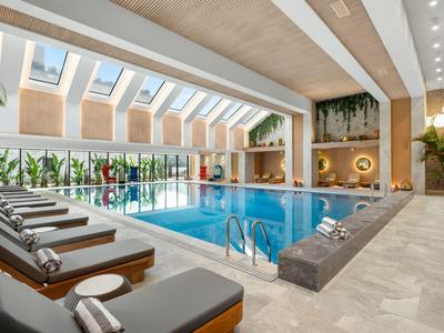 Piscine intérieure moderne avec chaises longues et grandes fenêtres dans un hôtel.