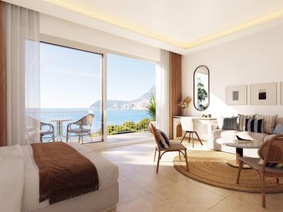 Helles Hotelzimmer mit Meerblick, Balkon und modernem Interieur in warmen Farben.