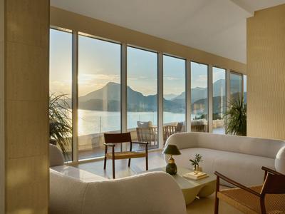 Modern eingerichteter Hotelzimmer mit großer Fensterfront und Berg- und Seeblick.